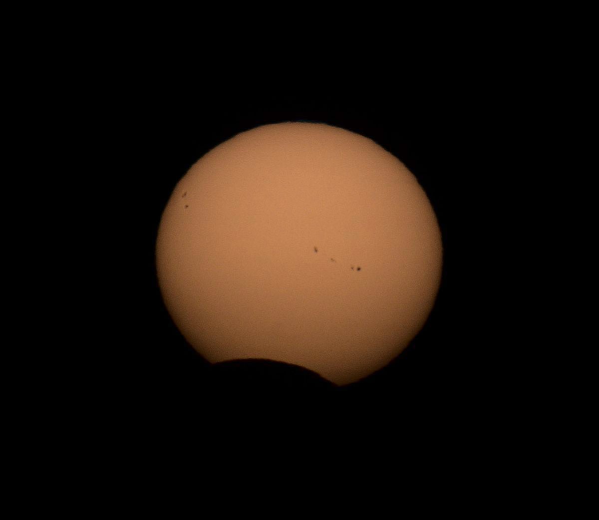 A partial solar eclipse – the end of the Great American Eclipse of 21 August 2017, taken at sunset from Pleinmont  by Elaine Mahy. Sunspots are visible in this shot taken with a Baader Astrosolar Safety Film filter over a 600mm camera lens. The moon is visible in silhouette, overlapping as a dark 'bite' across the Sun. (29628275)