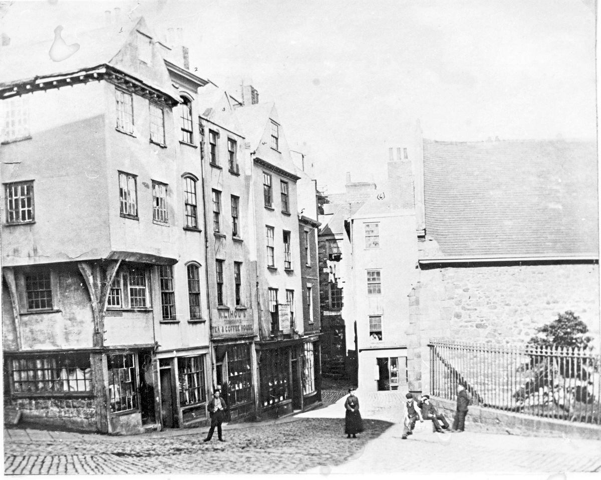 The corner of Fountain Street and Hill Street by the Town Church, St. Peter Port. There was M. Griffin, boot and shoe maker; Mrs. Lihou, Eating House; Rose Le Nepuev, (?) feather bed and mattress maker; Mrs. Hayward, China glass and earthenware. Pictures in the book Guernsey As It Used To Be by WJL Hugo...... (29407795)