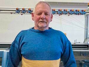 Martyn Lunn infront of the Channel Jumper knitting machine, wearing their Ukraine jumper. (30641408)