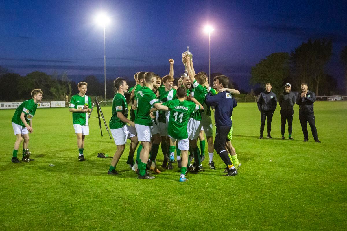 The Island U18 coaches, right, watch on proudly as captain Seb Vance lifts the Stranger Cup surrounded by his delighted teammates last night at Blanche Pierre where they beat North 5-1. (Picture by Luke Le Prevost, 30805034)