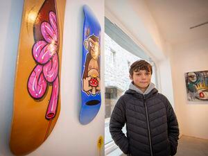 Picture by Sophie Rabey.  22-01-22.   âTransformation - The Beginning of an Artistic Journeyâ Street Art Exhibition in Mill Street.  Opening Day.  Theo Hollyer-Hill (aged 12) next to skateboard art that he likes in the exhibition.. (30418715)