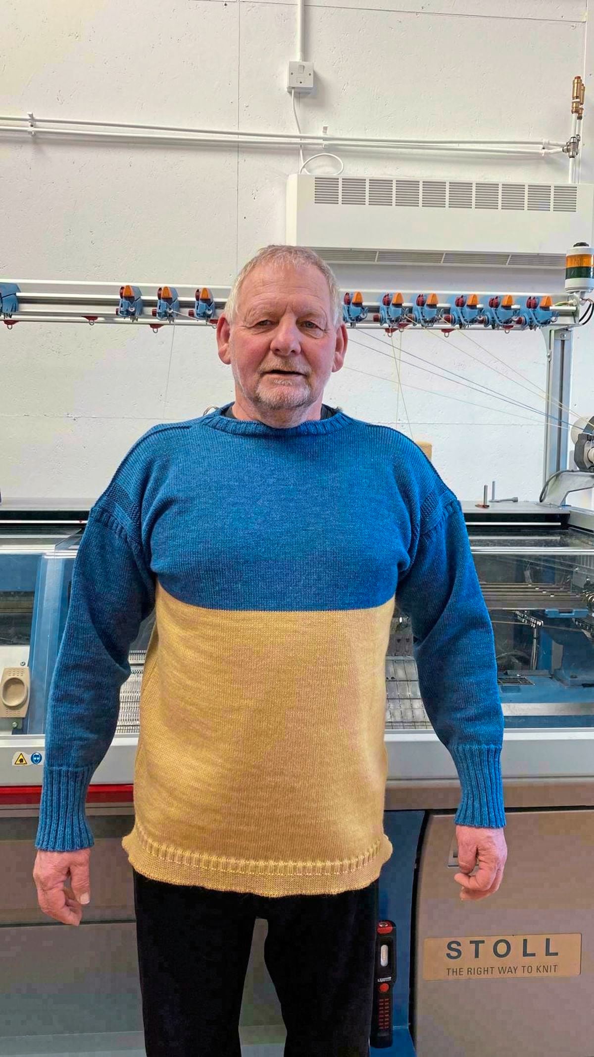 Martyn Lunn in front of the Channel Jumper knitting machine, wearing a Ukraine jumper.