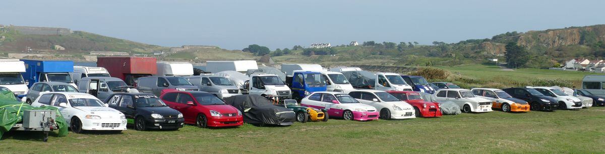Ready for action at the weekend. Guernsey Kart and Motor Club racers and their support vans  , some containing the karts and motorbikes, wait in readiness on  Braye Common with the Victorian Fort Albert  and the Arsenal on the hillside behind them. 
Picture by David Nash, 10-09-23 (32523378)