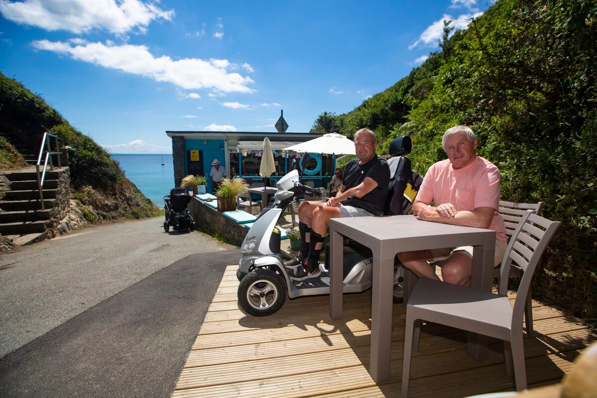The decking at Saints Bay kiosk has been rebuilt to make it accessible for wheelchair users and for Guernsey Disability Alliance vice-president David Rowlinson, who uses a mobility scooter. The man behind the project is St Martin’s senior constable Dave Beausire (right). (Picture by Peter Frankland, 31000516))