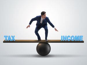 Businessman balancing between income and tax in business concept (31782121)