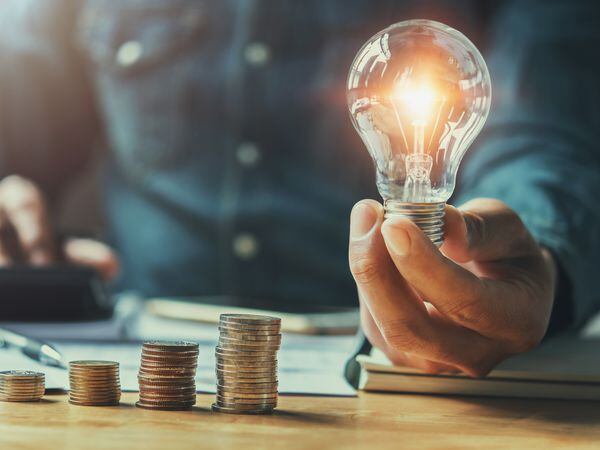 business man hand holding lightbulb with using calculator to calculate and money stack. idea saving energy and accounting finance in office concept (32574838)