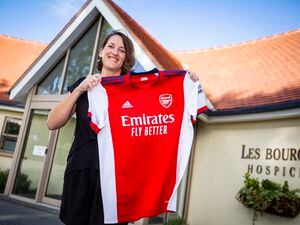 Picture by Luke Le Prevost. 26-09-22..Les Bourgs Hospice are holding a silent auction of a signed Arsenal football shirt by retired player Nigel Winterburn donated by a WatchLotto competition prize winner. Fundraising administrator Liz Stonebridge holding the shirt. (31306950)